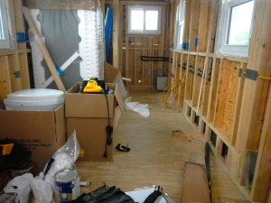 Interior of house. Looking back right is kitchen and back left is bathroom. Refrigerator is blocking bathroom walls. 